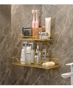 Close-up of golden wall-mounted metal storage rack for toiletries on marble wall