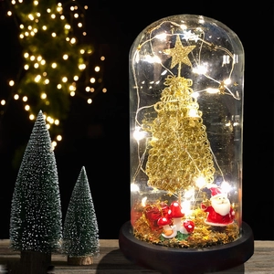 Close-up of glass dome with golden Christmas tree, Santa figurine and LED lights