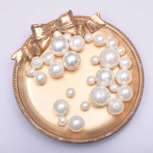 Various sizes of white round faux pearls in a gold tray for DIY jewelry making