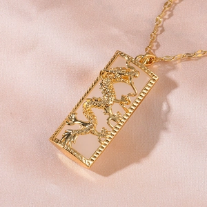 Gold dragon relief pendant necklace with pink inlay on silk background