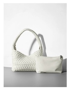 Dettaglio della borsa a spalla intrecciata bianca con pochette interna su superficie neutra