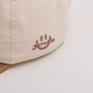 Casquette de bébé beige à séchage rapide avec broderie smile et détails latéraux