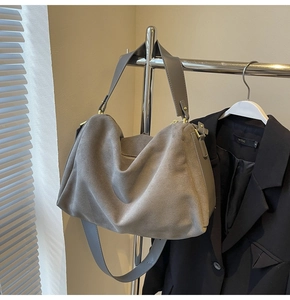 Gray suede crossbody baguette bag hanging on a hanger with wide strap detail