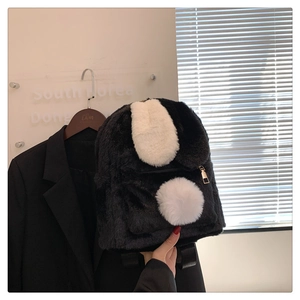 Detail of soft black plush backpack featuring white rabbit ears and golden metal zipper