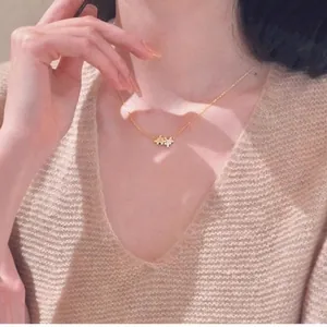 Detail of 14K gold-plated puzzle pendant with zircon stones on a knit sweater background