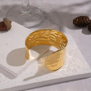 Detail view of wide hammered texture cuff bracelet in 18K gold plated stainless steel