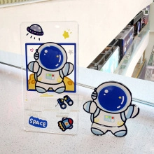 Close-up of blue and white astronaut acrylic phone stand with space lettering and charms