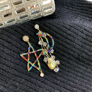 Detail view of colorful rhinestone star and moon earrings with tassels on black fabric