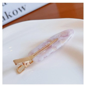 Close-up of pink marble pattern hair clip with gold metal base on a white ceramic plate