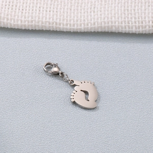 Polished stainless steel baby foot pendant with lobster clasp on grey surface