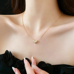 Detail of a gold heart pendant necklace with unique hammered texture on thin metal chain