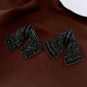 Elegant black crystal bow earrings with silver needles on dark velvet background