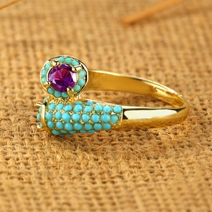 Vintage gold ring with purple gemstone and turquoise beads on burlap background