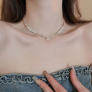 Détail du collier de perles à nœud argenté porté par un mannequin pour un look élégant
