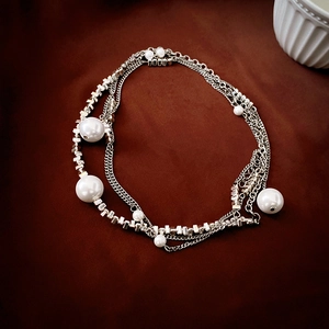 Detail view of multi-layer necklace with silver beads and pearls on dark brown velvet