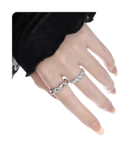 Macro detail of silver intertwined knot ring and slim pavé band on a model's hand