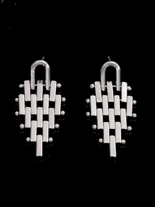 Macro detail of silver geometric trapezoid pendant earrings with a mirror finish on black background