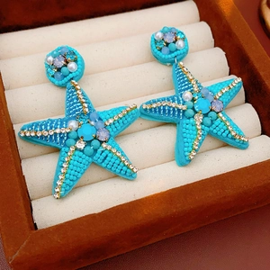 Macro shot of turquoise starfish earrings with bead inlay and pearls in a velvet box