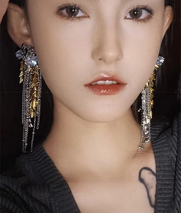 Close-up of elegant gold tassel earrings with zircon studs worn by a professional model