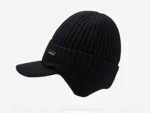 Dettaglio del cappello in maglia nera con texture a coste e paraorecchie invernali