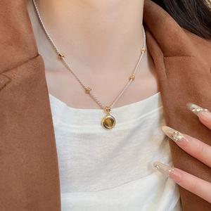 Close-up of tiger eye stone pendant necklace on a model with caramel suit