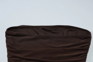 Detail view of the brown ruched fabric and elastic mesh stitching on the slim dress