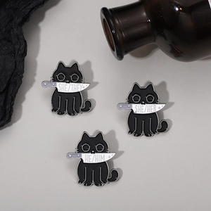 Detail showing black cat enamel pins with knives and she her they pronouns