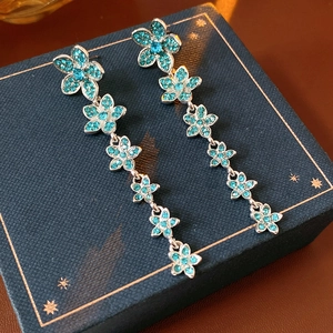 Gros plan de boucles d'oreilles vintage en argent avec fleurs en zircon bleu sarcelle