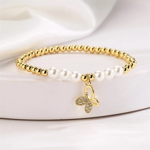 Macro detail of gold beaded bracelet with pearls and a crystal butterfly charm