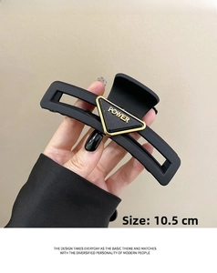 Detail view of 10.5cm matte black claw clip with gold POWER triangle emblem