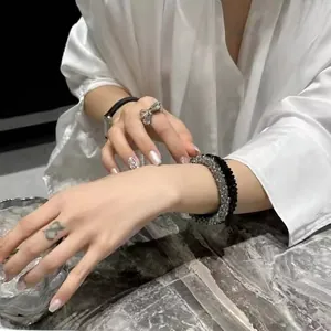 Close-up of stacked crystal beaded bracelets and rhinestone bow ring on a model