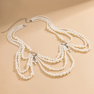 Macro detail of multi-layered pearl body chain with silver metal fringe tassels