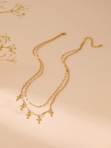Close-up of double-layer gold necklace featuring five small cross pendants on a bar