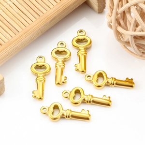Set of 6 gold stainless steel key pendants for DIY jewelry making on white surface
