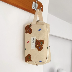 Close-up of quilted beige makeup bag with brown bear patterns hanging on a wooden hook