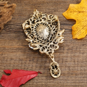 Vintage gold hollow water drop brooch and pendant with a detailed pin on a wooden background
