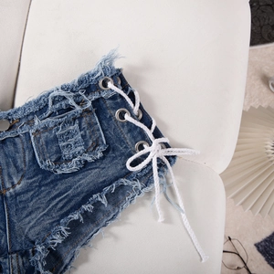 Dettaglio di pantaloncini di denim blu con lacci laterali e orlo sfrangiato su tessuto