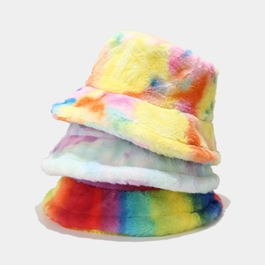 Three stacked tie-dye fuzzy bucket hats in colorful yellow, blue, and rainbow plush textures