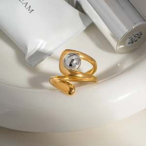 Dettaglio di un anello dorato con perla d'argento su un vassoio di ceramica bianca