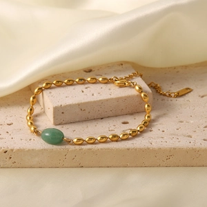French retro gold bead bracelet featuring an oval green natural stone on silk background