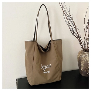 Detail view of khaki leopard print tote bag with merci print on dark surface