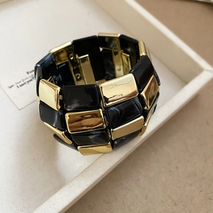Close-up of a wide stretch bracelet with black marble acrylic and gold metal squares