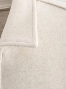 Detailed close-up showing the high-quality stitching on the beige wool blend jacket fabric