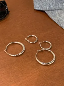 Detail view of two pairs of polished silver hoop earrings in large and small sizes