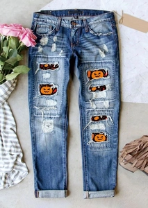 Détail d'un jean déchiré bleu avec des écussons imprimés de citrouilles et de crânes d'Halloween