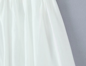 Detailed close-up of white textile fabric texture and pleated detail on casual camisole
