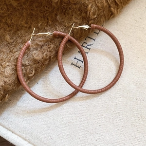 Detail of brown leather texture hoop earring on plush fabric with vintage aesthetic