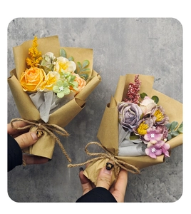 Miniature silk rose bouquets in kraft paper packaging held against a neutral grey wall