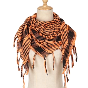Detail of orange and black houndstooth pattern scarf with tassel fringe edges