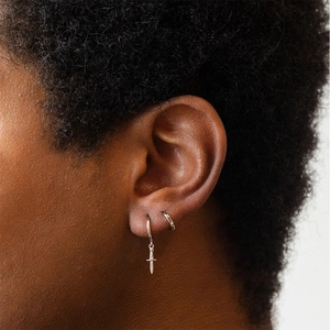 Detail view of silver S925 sterling silver hoop earrings with a small dagger pendant on model